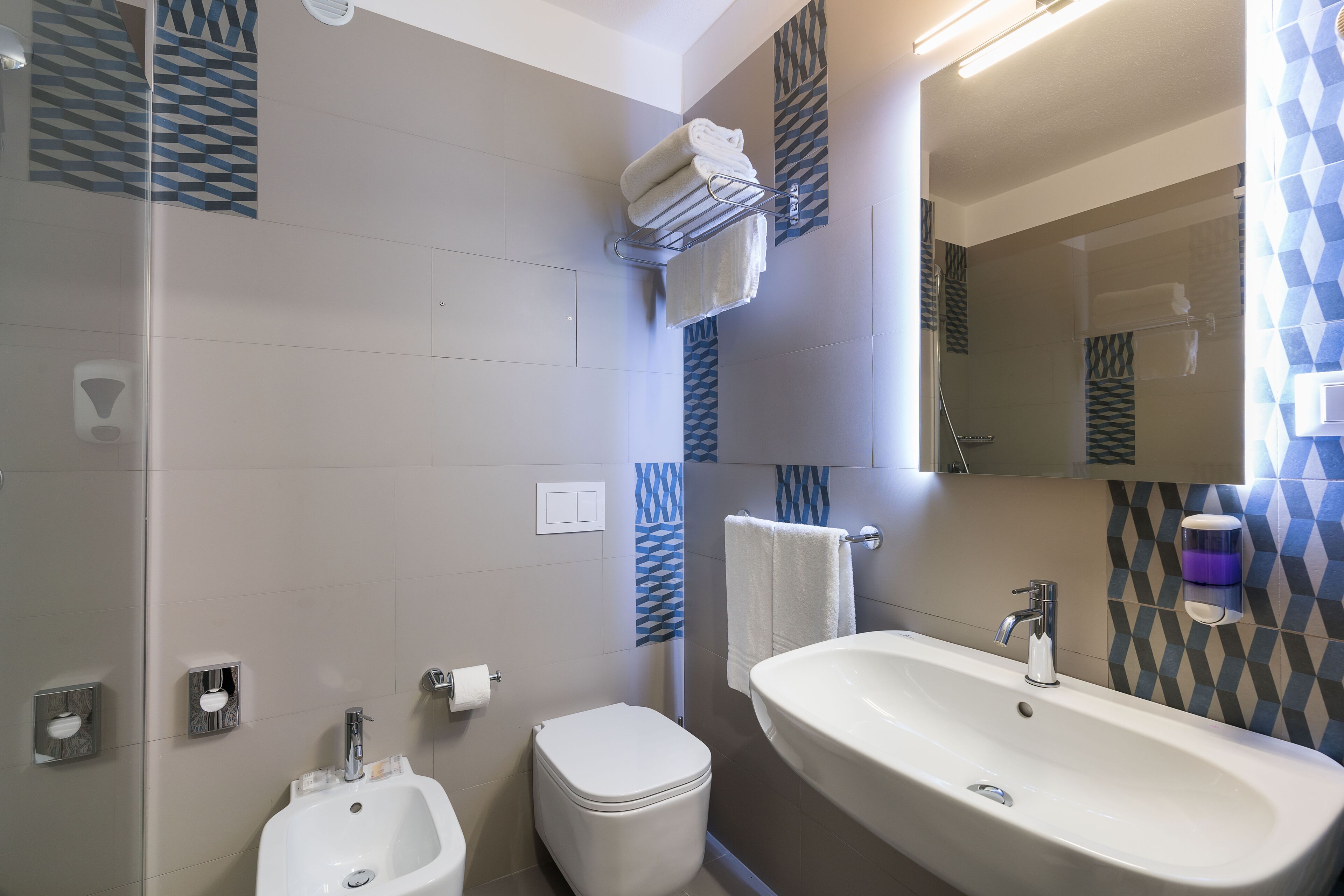 A modern bathroom with a bidet, toilet, sink, and a mirror.