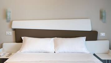 A hotel room with a bed, bedside tables, a telephone, and wall-mounted light fixtures.