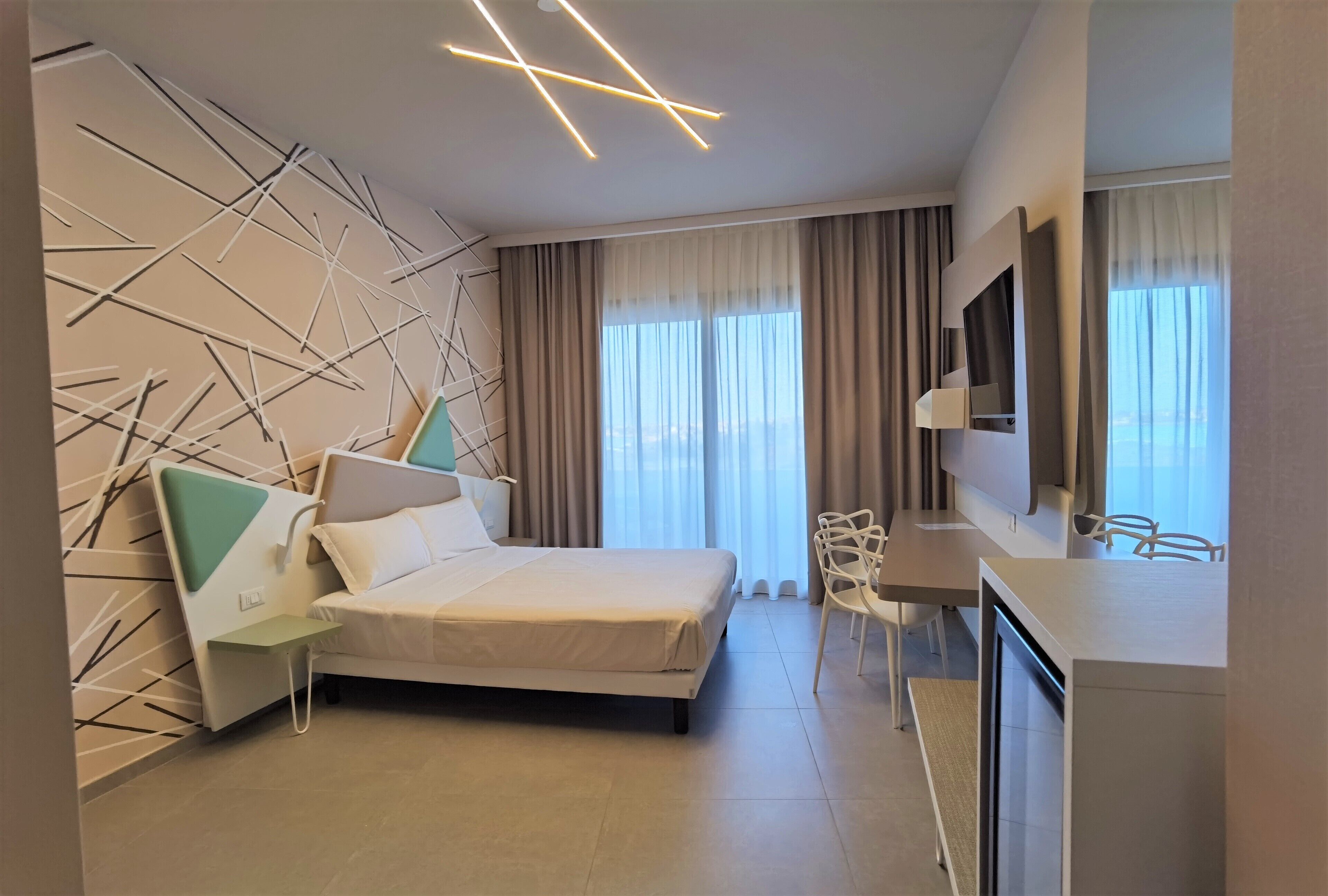 Habitació d'hotel moderna amb llit, escriptori i televisió.
