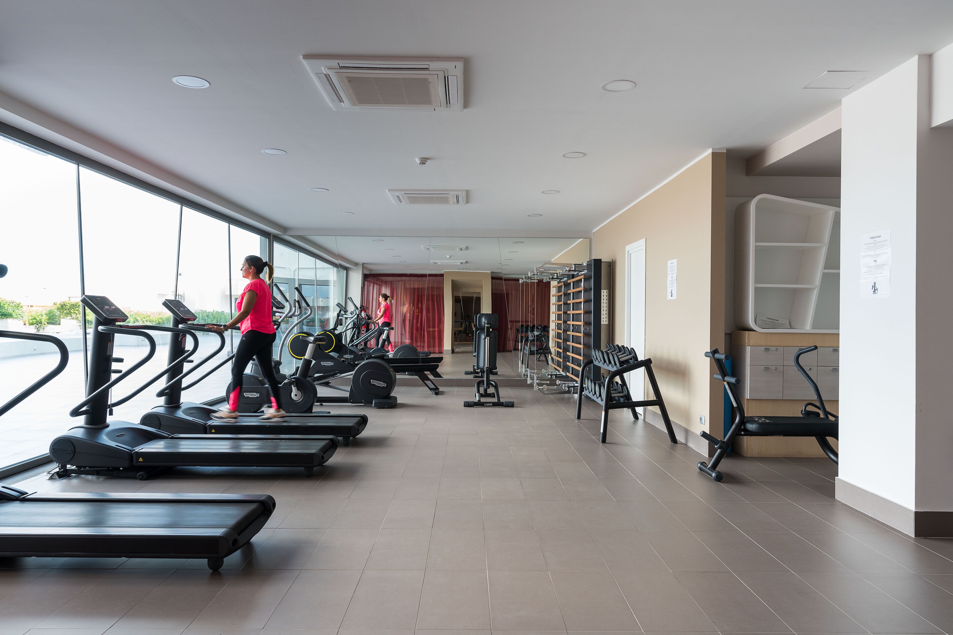 Een fitnessruimte met loopbanden, gewichten en trainingsapparatuur.