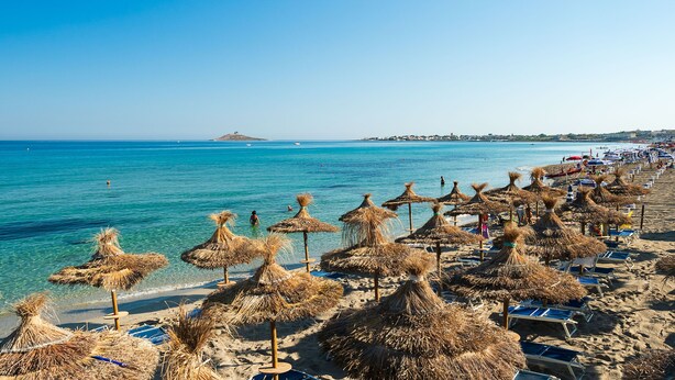 A beach with thatched umbrellas and sun loungers, clear blue water, and a distant island. - Saracen Sands Hotel & Congress Centre (Isola delle Femmine)
