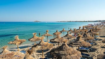 Aan een privéstrand, wit zand, ligstoelen, parasols