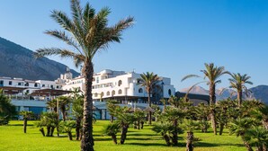 A hotel with a white facade, multiple balconies, and a lush garden with palm trees. - Saracen Sands Hotel & Congress Centre (Isola delle Femmine)