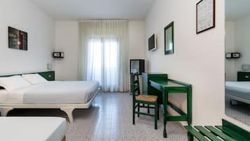 A hotel room with two beds, a desk, a chair, a mirror, and a window with curtains.