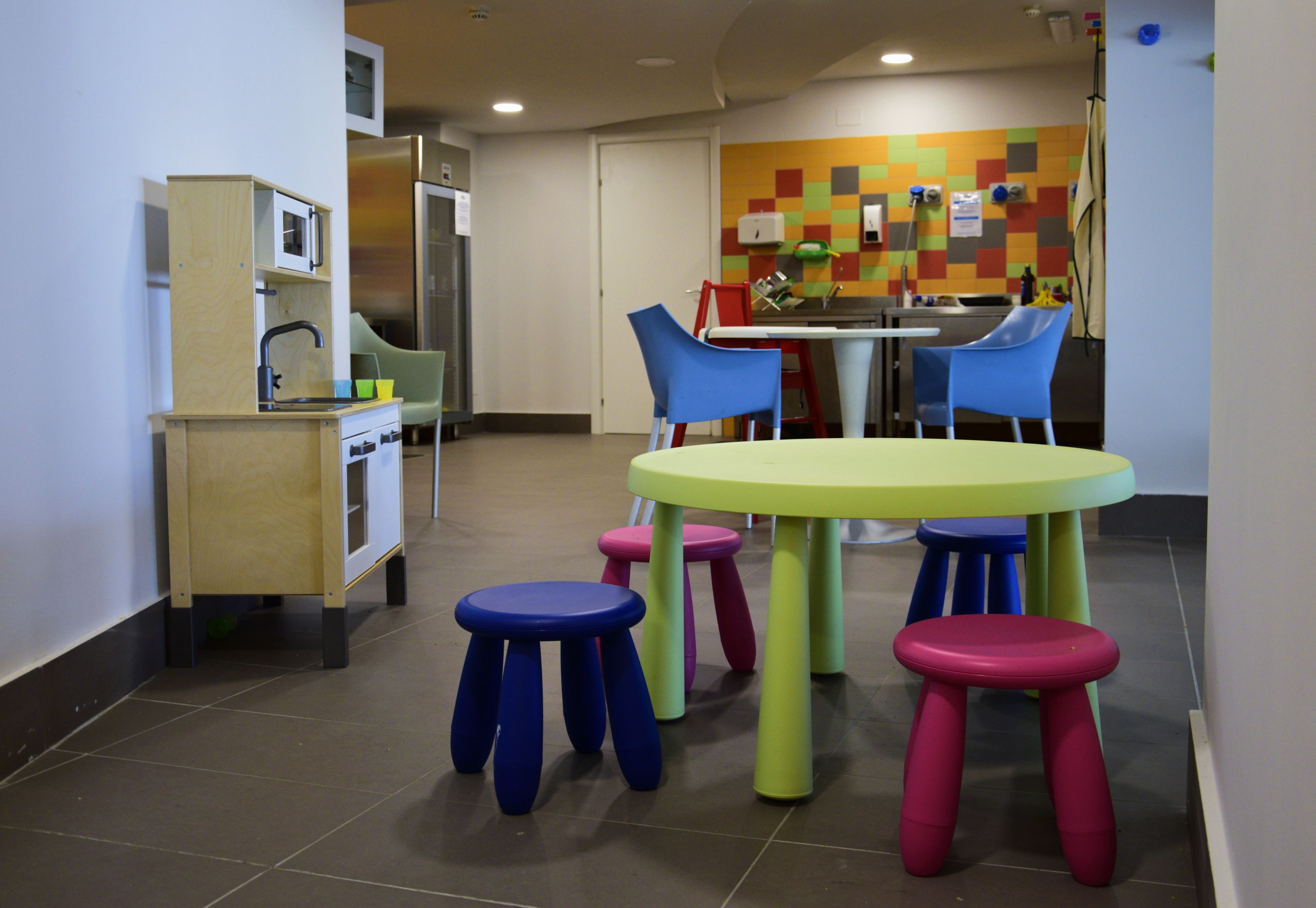 A children's play area with a round table and colorful stools.