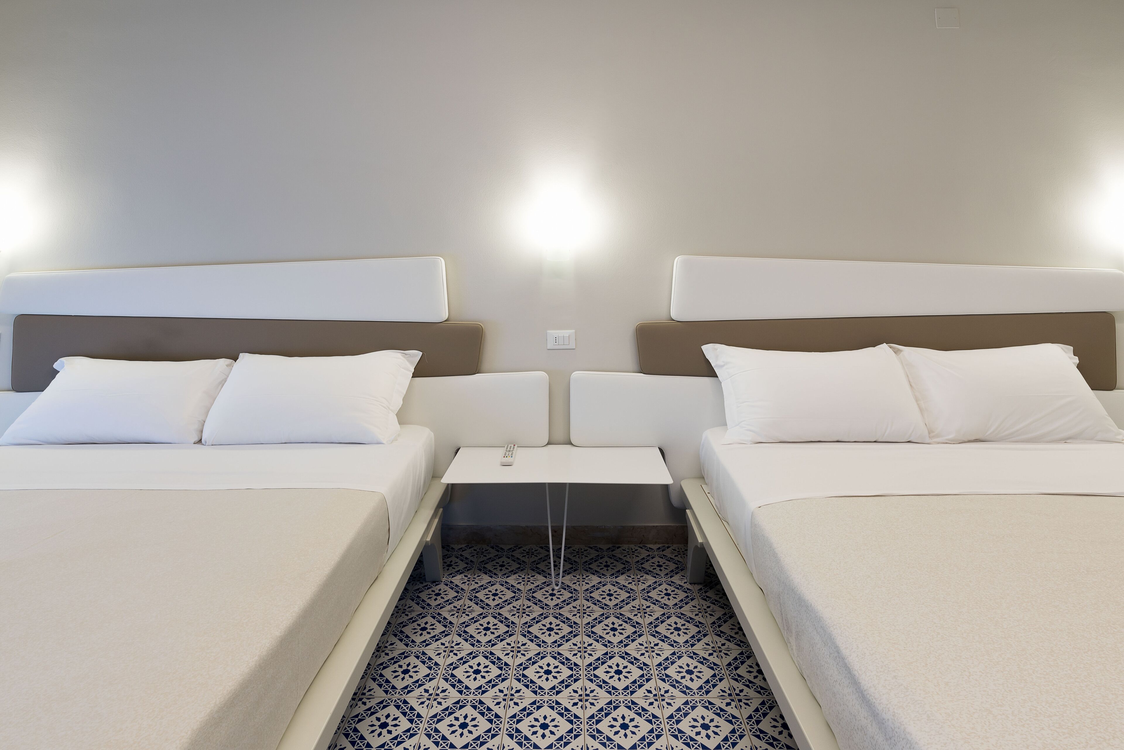 A hotel room with two beds, a small table, and a patterned floor.