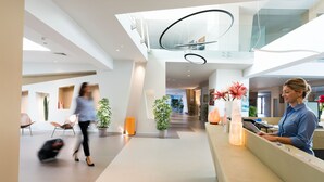 A modern hotel lobby with a reception desk, seating areas, and a glass staircase. - Saracen Sands Hotel & Congress Centre (Isola delle Femmine)