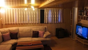A cozy living room with a beige sofa, a wooden coffee table, and a television on a stand.