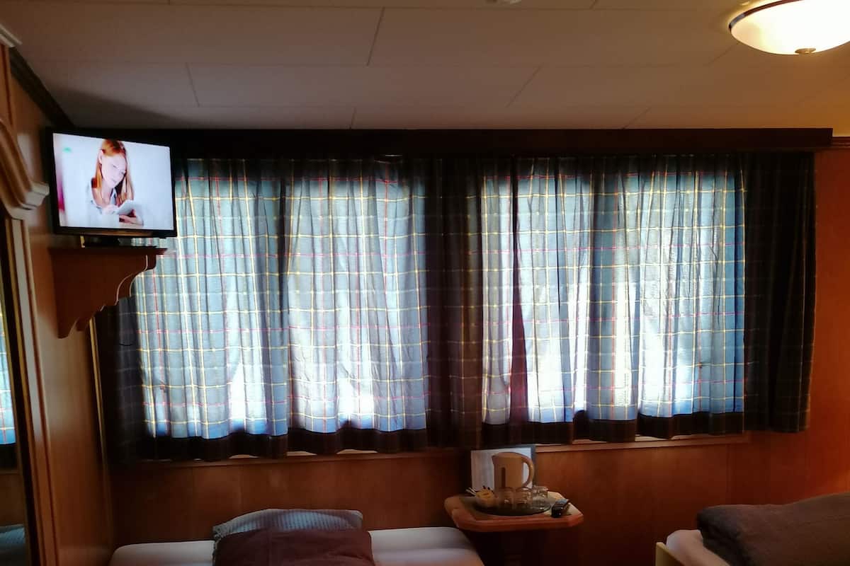 Ein Hotelzimmer mit einem Bett, einem kleinen Tisch mit einer Tasse, einem Sessel und einem Fernseher auf einem Schrank.