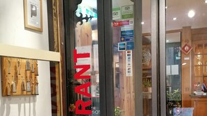 A restaurant entrance with a glass door, a wooden key rack, and various signs including one for 'HolidayCheck 2017'.