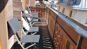 A balcony with seating and a view of a mountain.