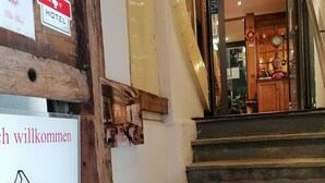A staircase leading to a hotel entrance with a sign reading "Willkommen" and a coat of arms.