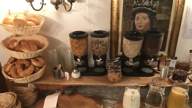 A breakfast buffet with bread, pastries, and various condiments.