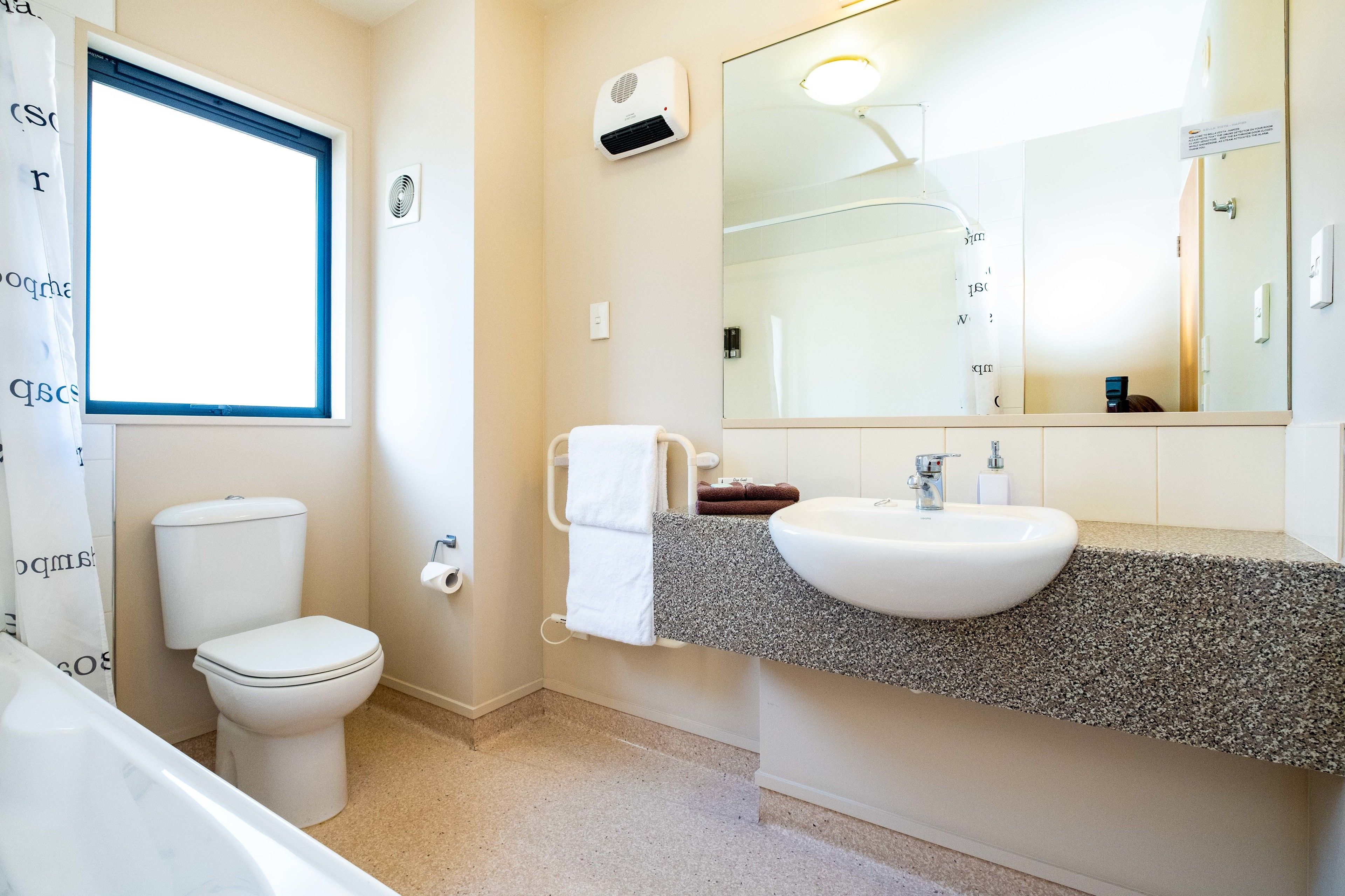 Un baño con inodoro, lavamanos y espejo.