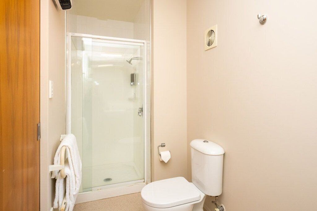 Une salle de bain avec une douche à parois de verre, des toilettes blanches et un porte-serviettes.