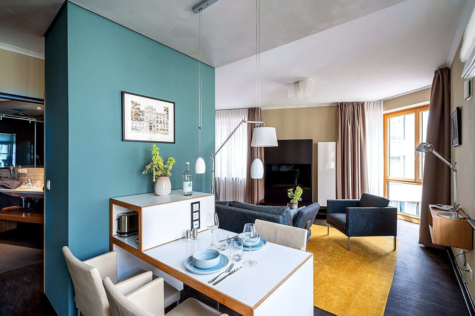 A modern living room with a dining area, a fireplace, and a large window with curtains.