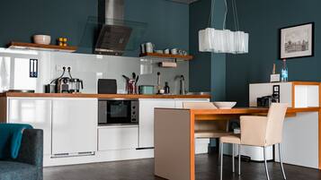A modern kitchen with white cabinetry, a built-in oven, and a dining area with a wooden table and chairs.