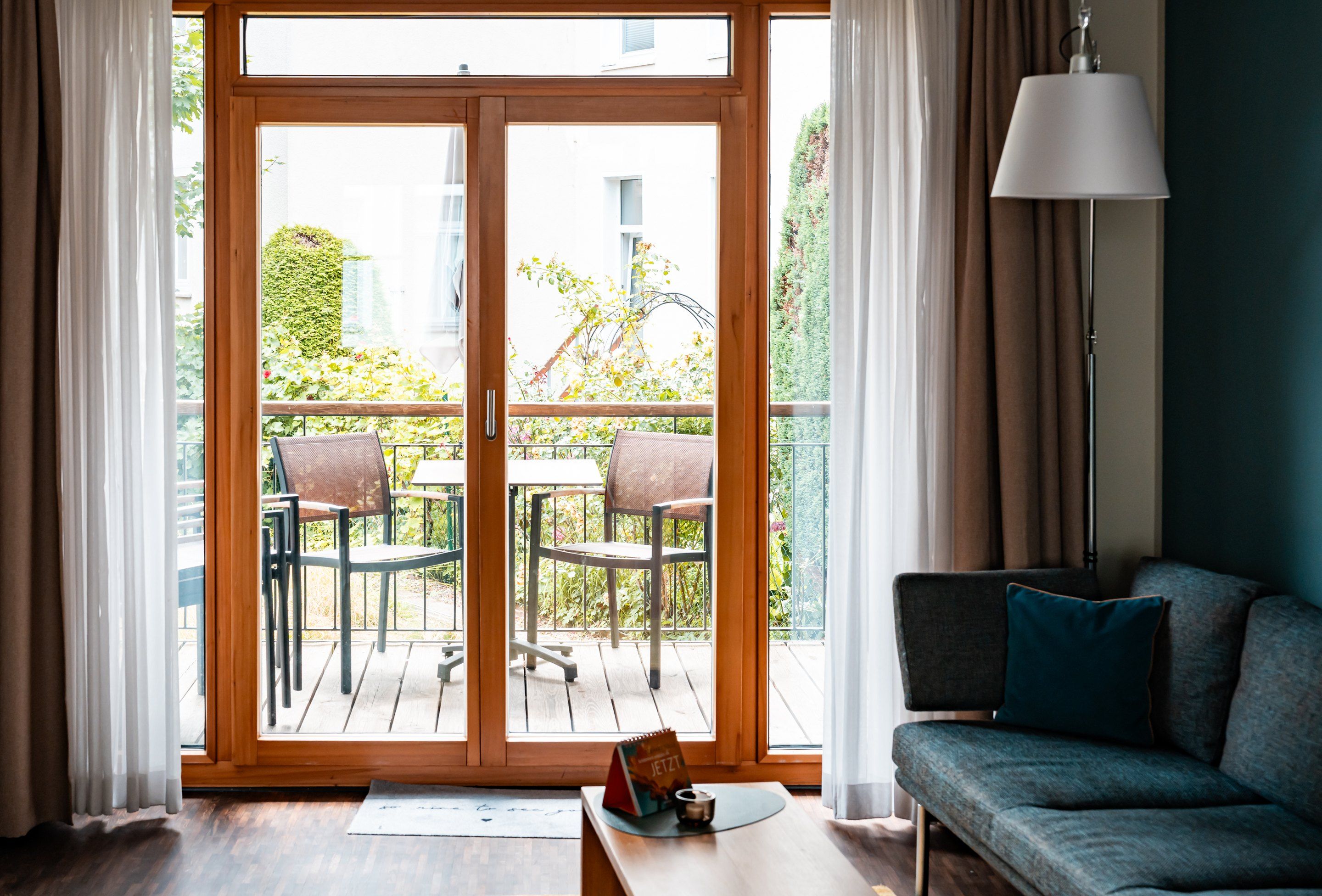Una habitación con puerta de vidrio corredera que da a un área de estar exterior con dos sillas y una mesa.