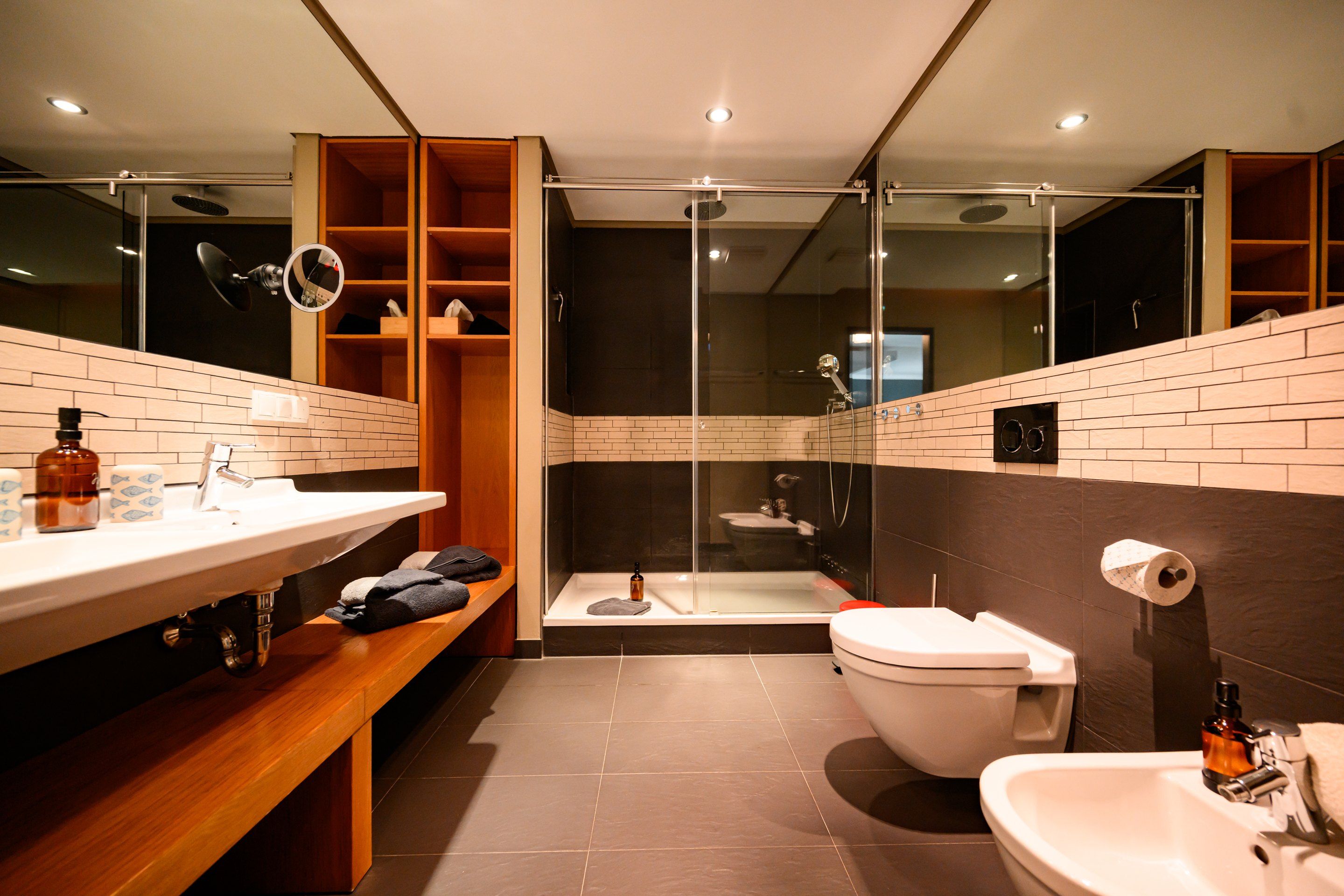 Ein modernes Badezimmer mit einer gläsernen Duschkabine, einer Toilette und einem Waschbecken mit Spiegel.