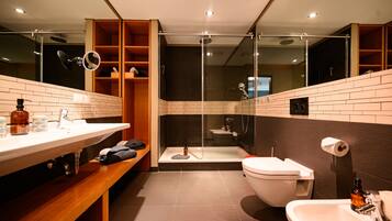 Ein modernes Badezimmer mit einer gläsernen Duschkabine, einer Toilette und einem Waschbecken mit Spiegel.