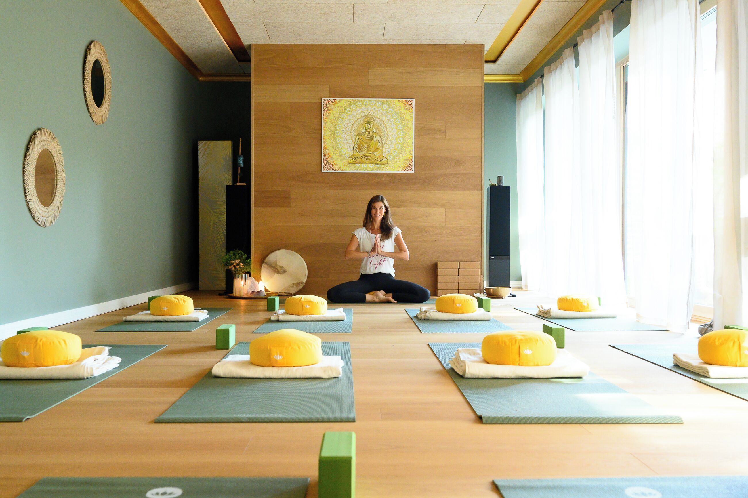 A yoga studio with mats, cushions, and a meditative statue on the wall.