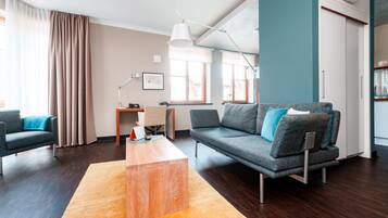A modern living room with a sofa, a coffee table, and a desk with a lamp.