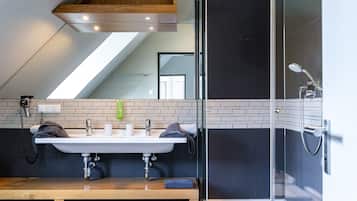 Ein modernes Badezimmer mit einem Waschbecken-Doppelplatz, einer Glasdusche und einem Oberlicht über dem Waschbecken.