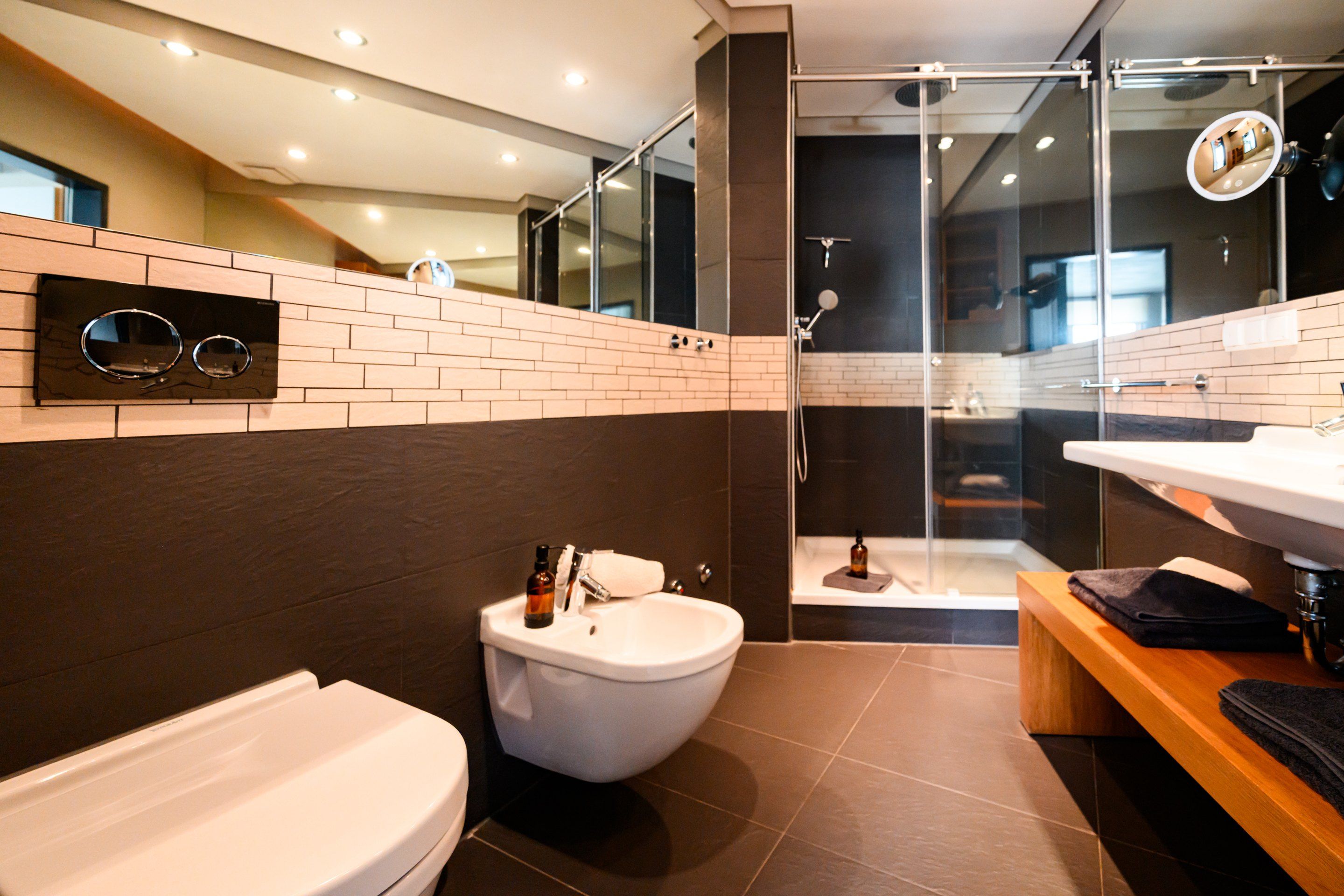 Un baño moderno con inodoro, lavamanos y zona de ducha.
