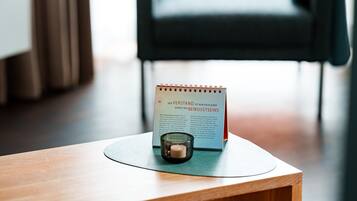 A notebook on a wooden table with a candle and a chair in the background.