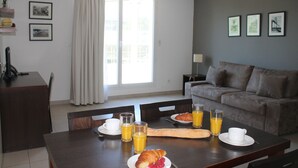 A dining area with a table set for breakfast, including croissants, fruit, and orange juice. - Residence Calypso (Marseille)