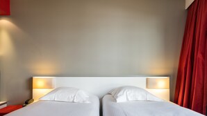 Una cama doble con sábanas blancas y dos lámparas de noche.