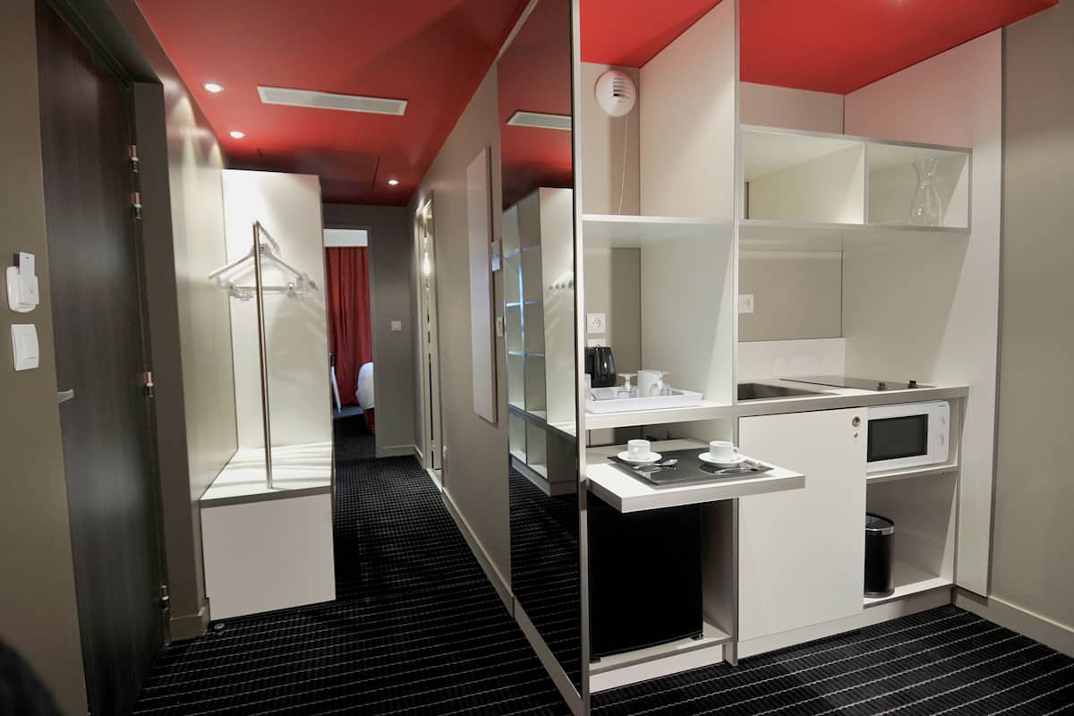 Una habitación de hotel moderna con kitchenette, vestidor y zona de ducha.