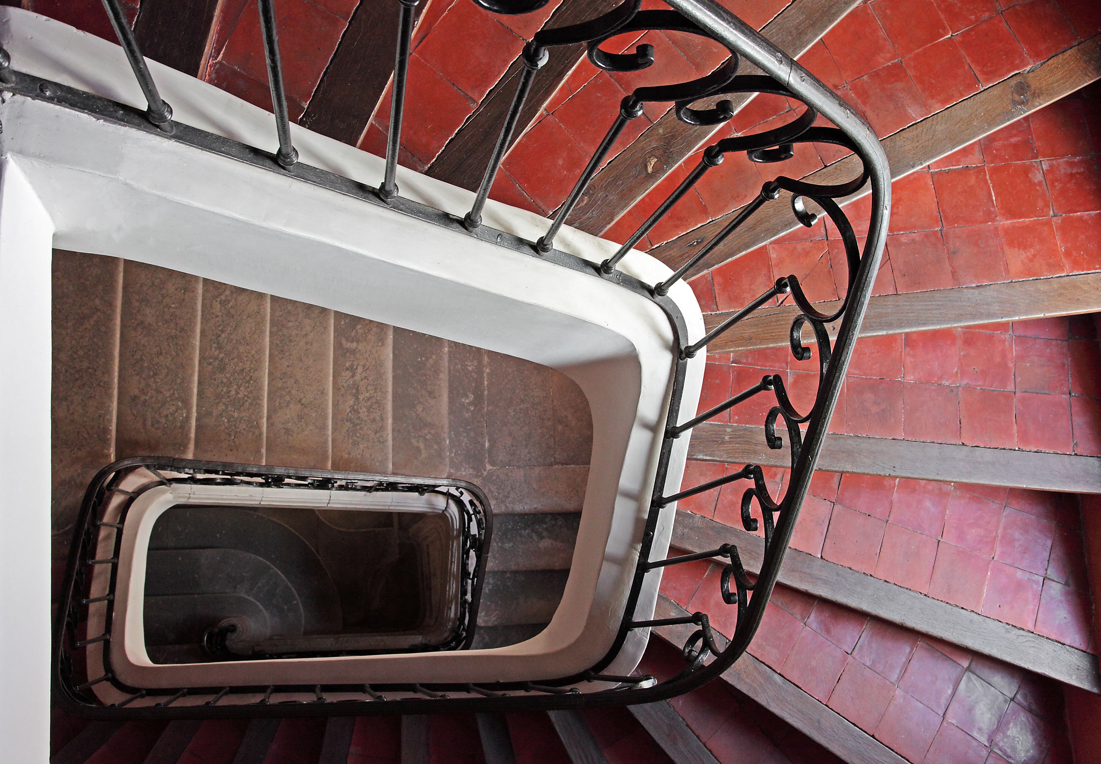 Una escalera de caracol con barandilla de metal y pasamanos blanco.