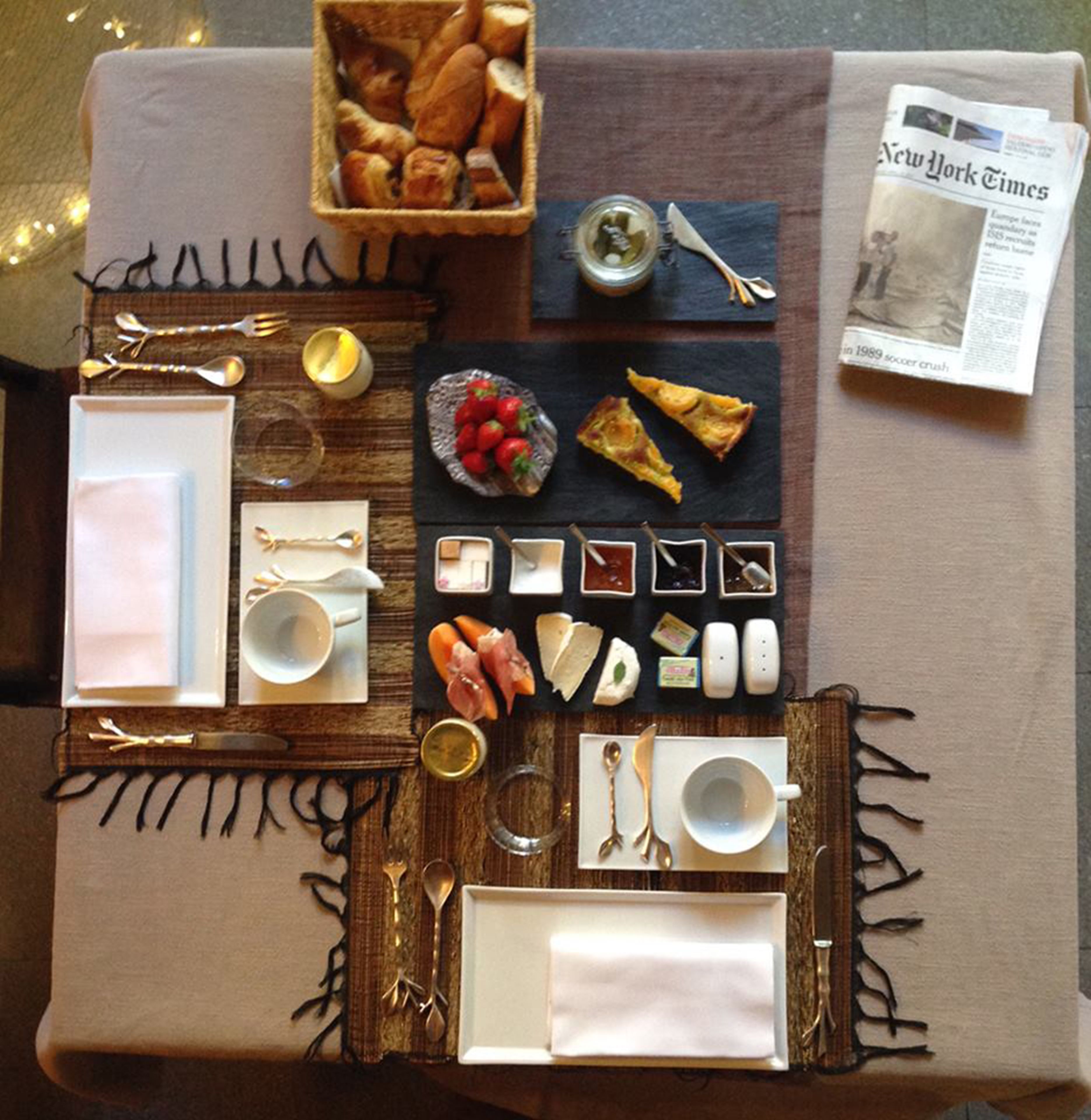 A table set with various food items, utensils, and a newspaper.