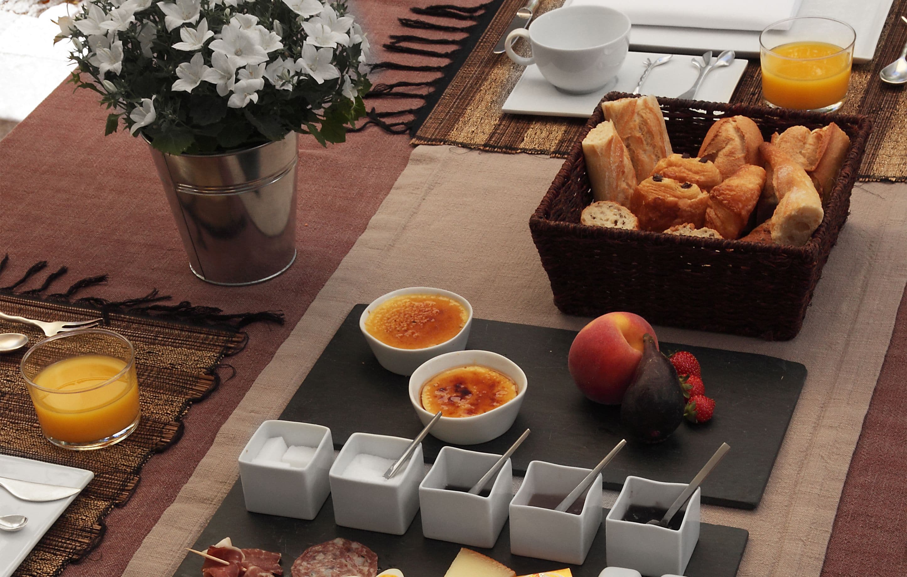 A breakfast setting with bread, fruit, and condiments on a table.
