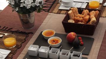 A breakfast setting with bread, fruit, and condiments on a table.