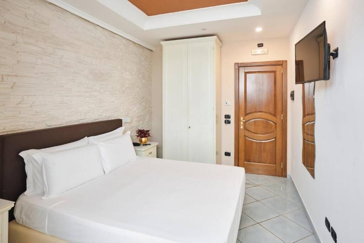 Una camera da letto con un letto, un comodino, un armadio, una TV e una porta.