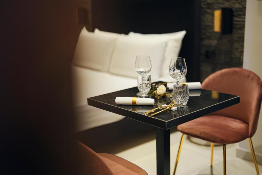Uma mesa de jantar com tampo preto, pés dourados e uma cadeira rosa.