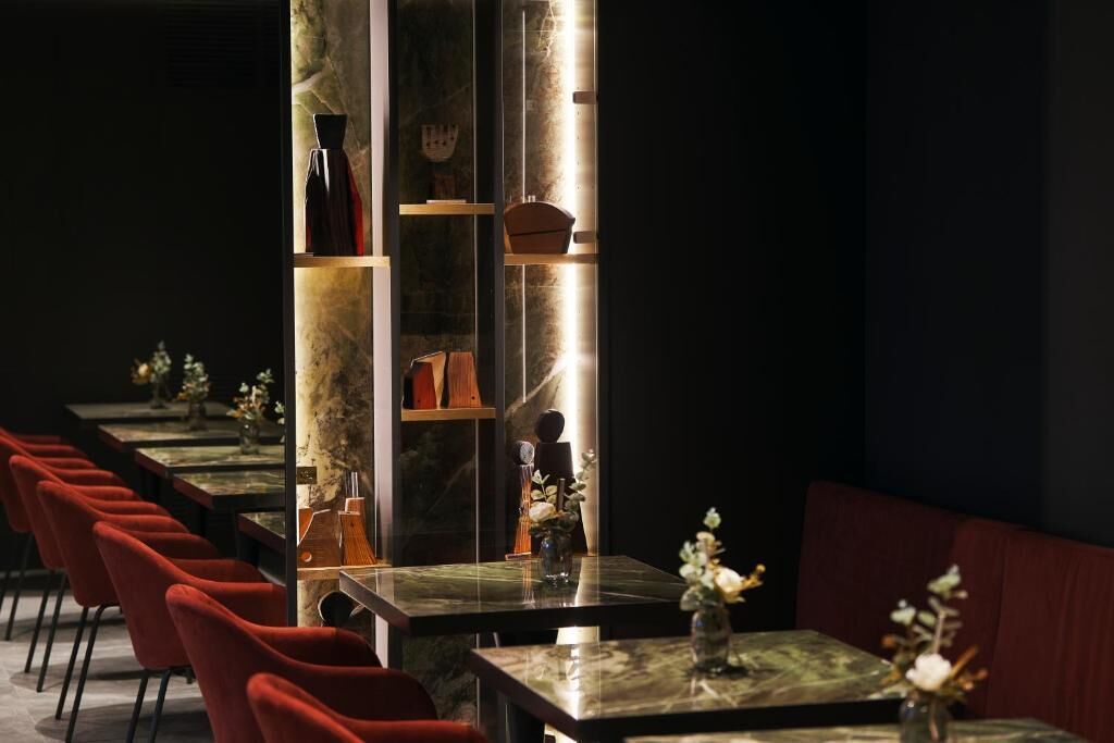Un ristorante con un lungo tavolo, sedie rosse e una colonna in marmo.