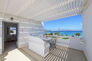 A balcony with a view of the sea and a bridge, white walls, and a table with chairs. - En Milo (Milos)
