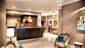 A hotel lobby with a reception desk, seating area, and a chandelier. - Galeón Mar del Plata (Mar del Plata)