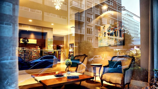 A hotel lobby with a seating area, a coffee table, and a view of the street and buildings outside. - Galeón Mar del Plata (Mar del Plata)