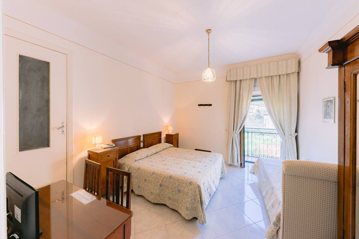 A bedroom with a bed, bedside tables, a desk, and a chair.