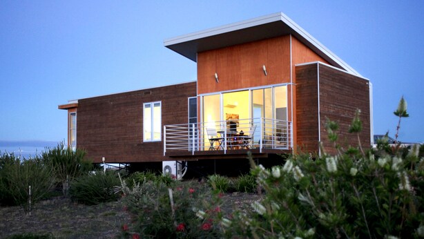 A modern house with a wooden exterior, a balcony with a railing, and a view of the sea. - Eco-luxe at Mount Avoca (Percydale)