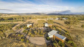 Una propiedad rural con varias construcciones, que incluye una casa principal con un garaje amplio, rodeada de campos y vegetación escasa.