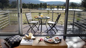 A dining area with a table set for two, a book, and a bowl of fruit. - Eco-luxe at Mount Avoca (Percydale)
