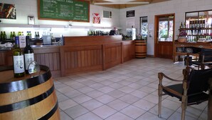 A bar area with wooden furniture, a counter with wine bottles, and a menu board. - Eco-luxe at Mount Avoca (Percydale)