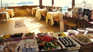A buffet setup with various food items and a coffee station in a well-lit room with a view of a ship. - Esans Hotel - Special Class (Istanbul)