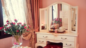 A room with a vanity, a mirror, a vase with flowers, a red chair, and a window with curtains. - Esans Hotel - Special Class (Istanbul)