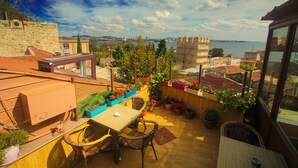 A rooftop terrace with a table and chairs, surrounded by potted plants and overlooking a cityscape and body of water. - Esans Hotel - Special Class (Istanbul)